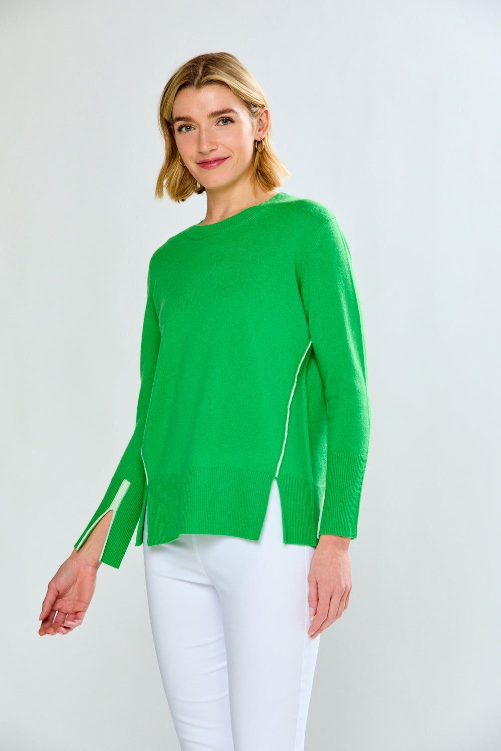 Woman wearing a green sweater with sheer panels on a white background
