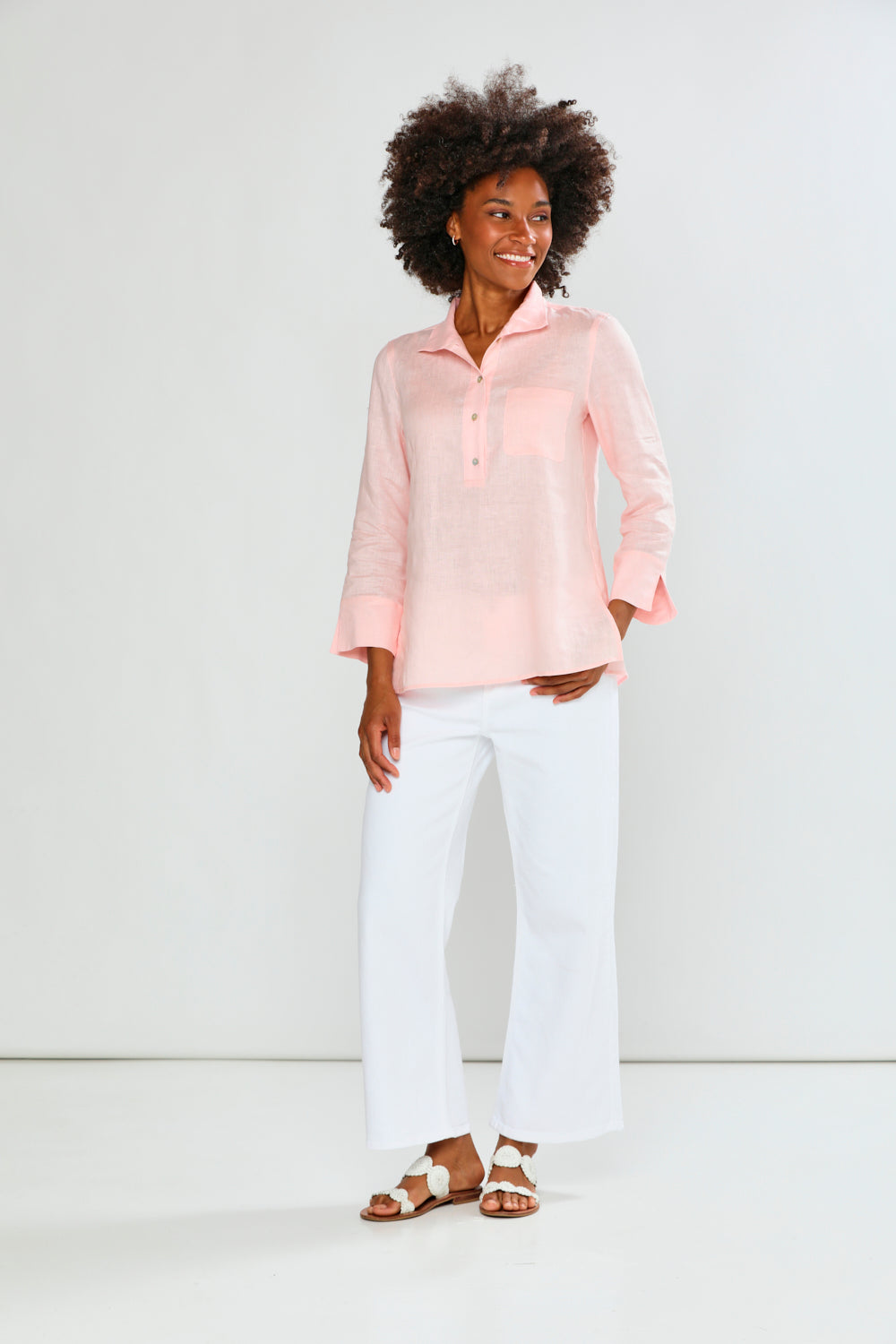 Woman wearing a light pink blouse and white pants on a white background