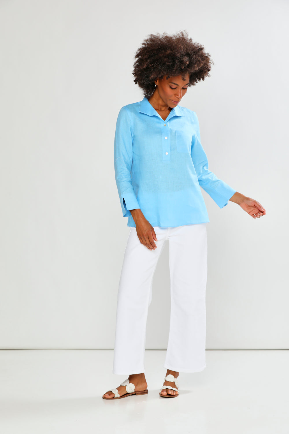 Woman wearing a light blue shirt and white pants on a white background