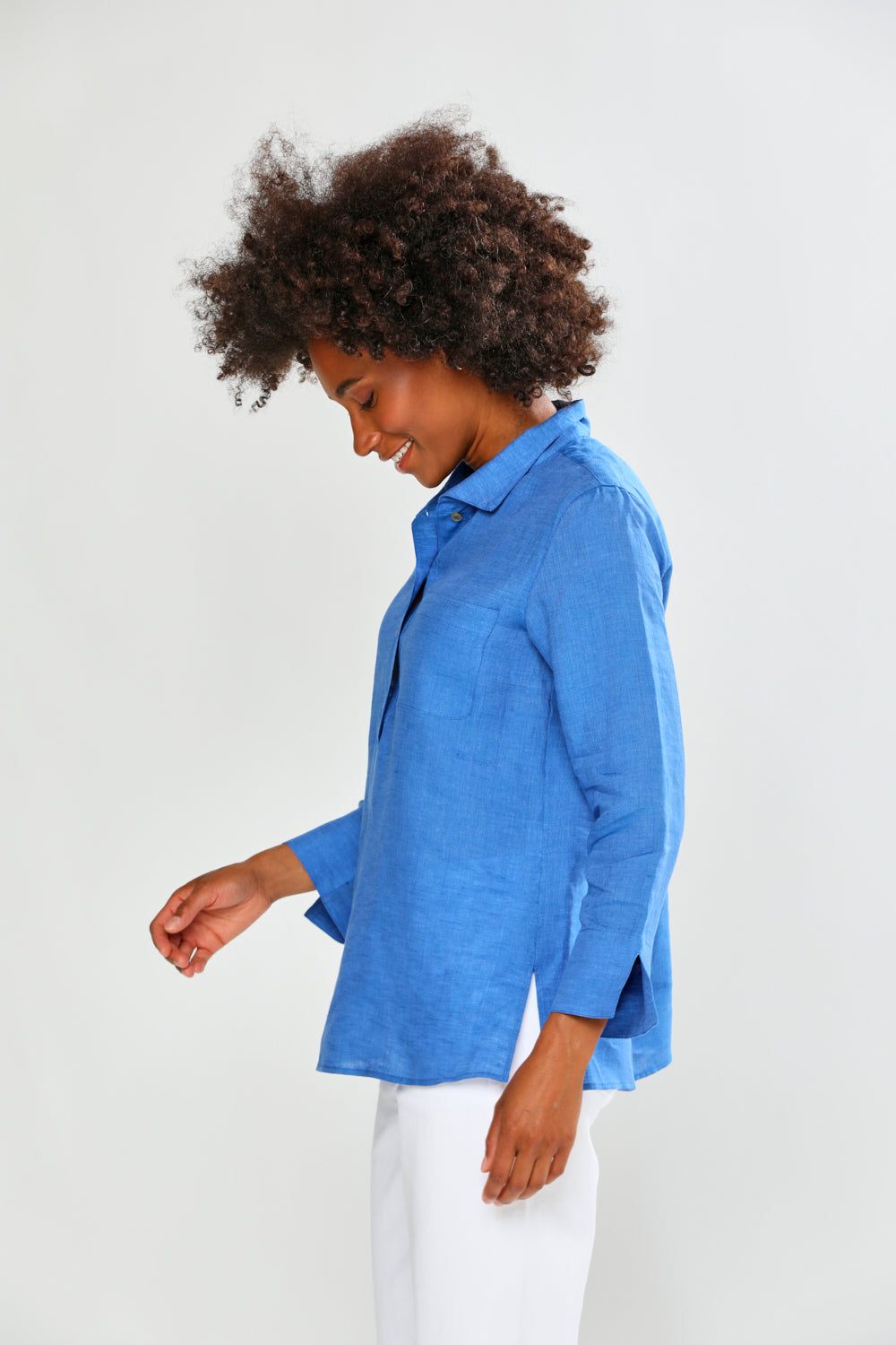 Woman wearing a blue shirt and white pants on a plain background
