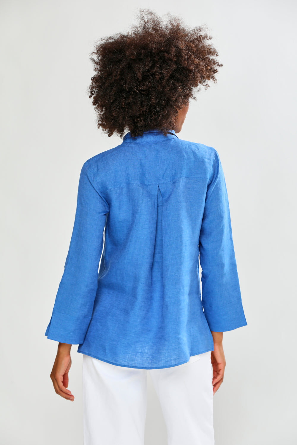 Person wearing a blue shirt and white pants on a plain background