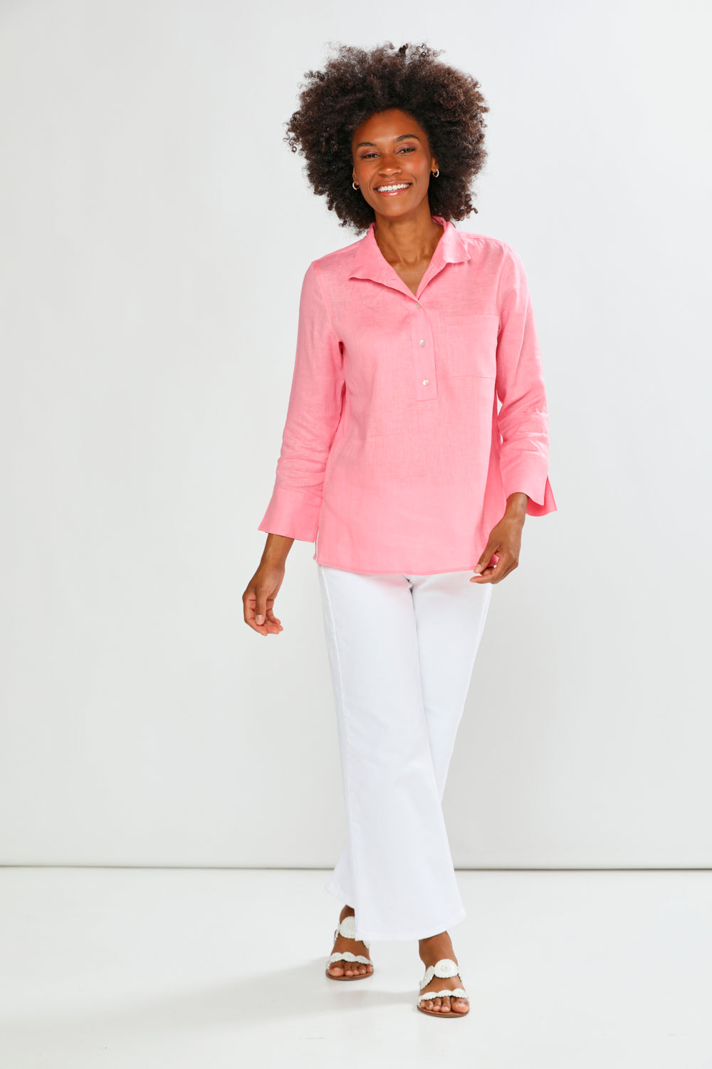 Woman wearing a pink shirt and white pants on a white background