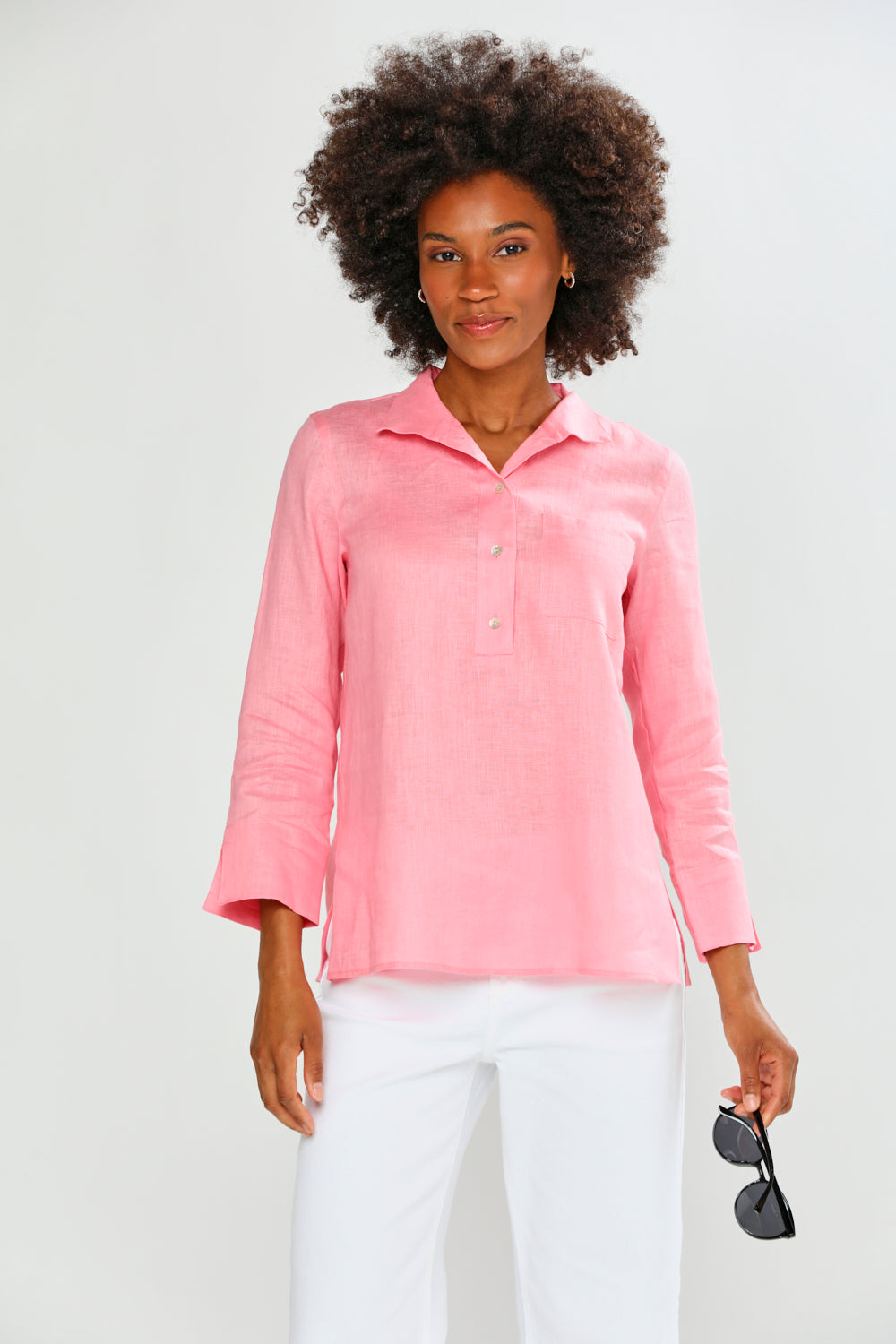 Woman wearing a pink shirt and white pants against a white background