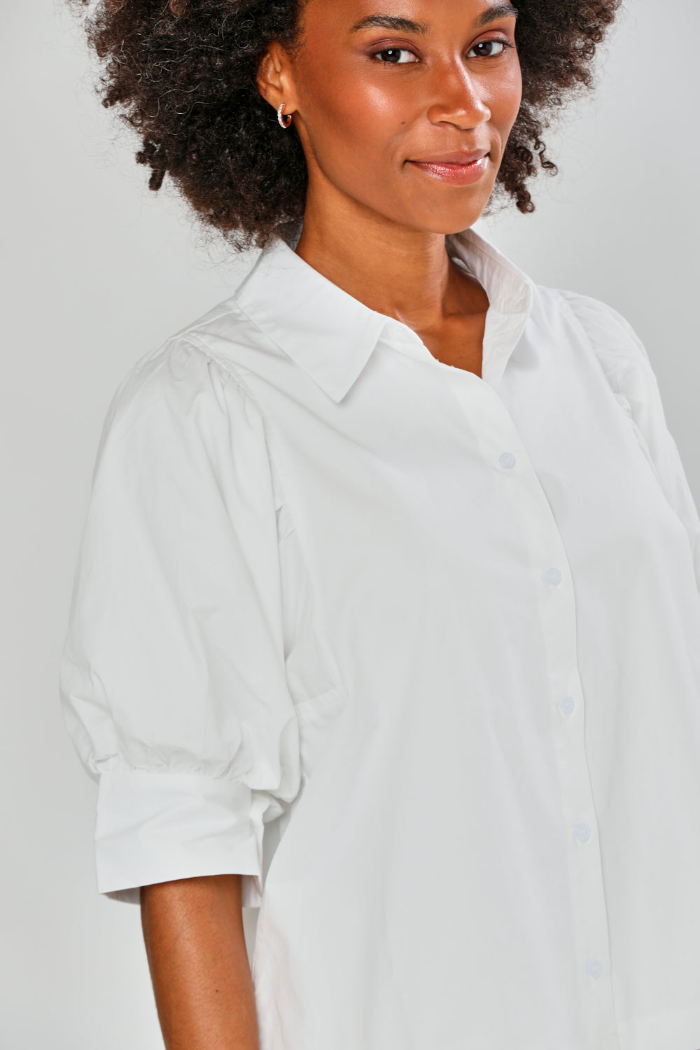 Person wearing a white shirt against a plain background
