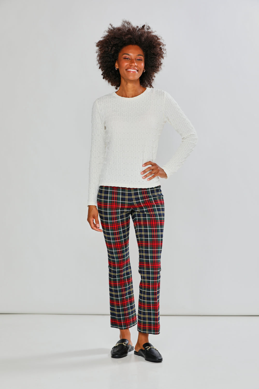 Woman wearing a white sweater and plaid pants on a white background