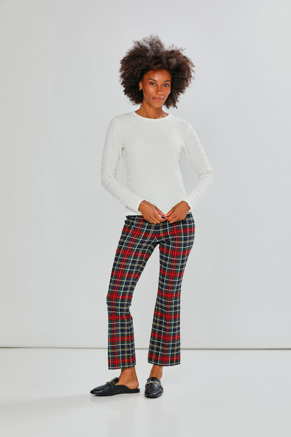 Woman wearing a white top and plaid pants on a plain background