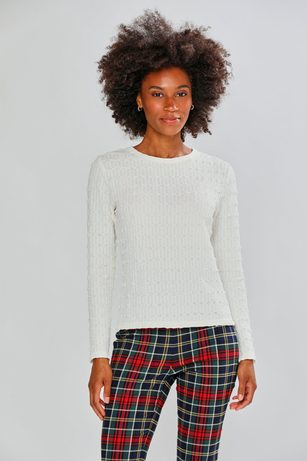 Woman wearing a white top and plaid pants on a plain background