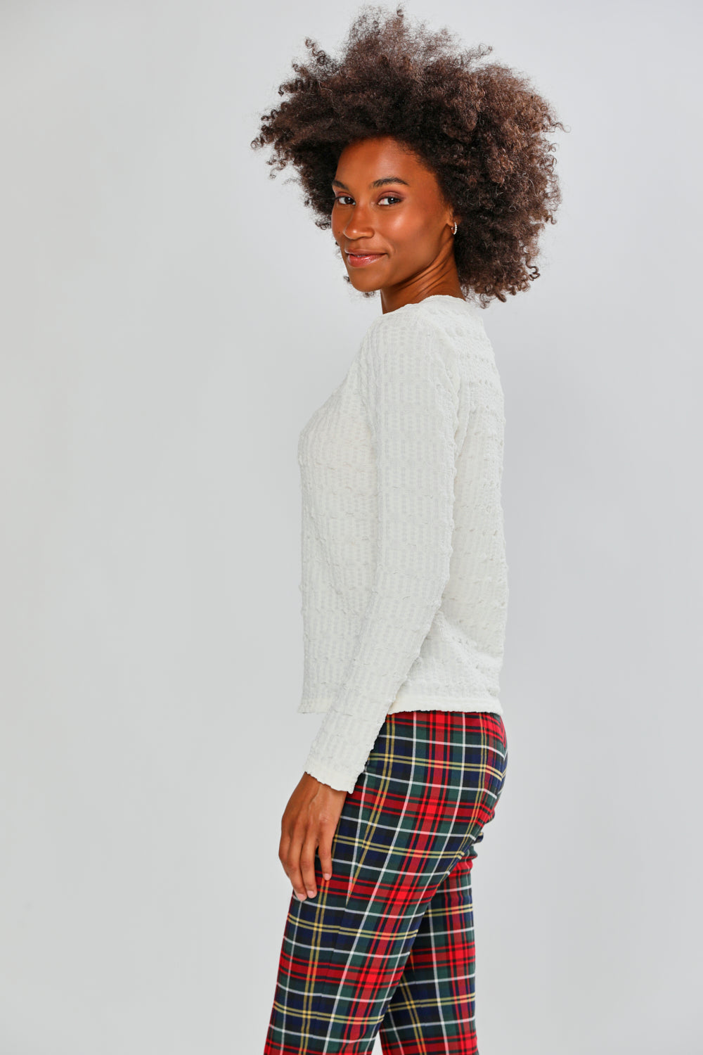Woman wearing a white top and plaid pants on a plain background