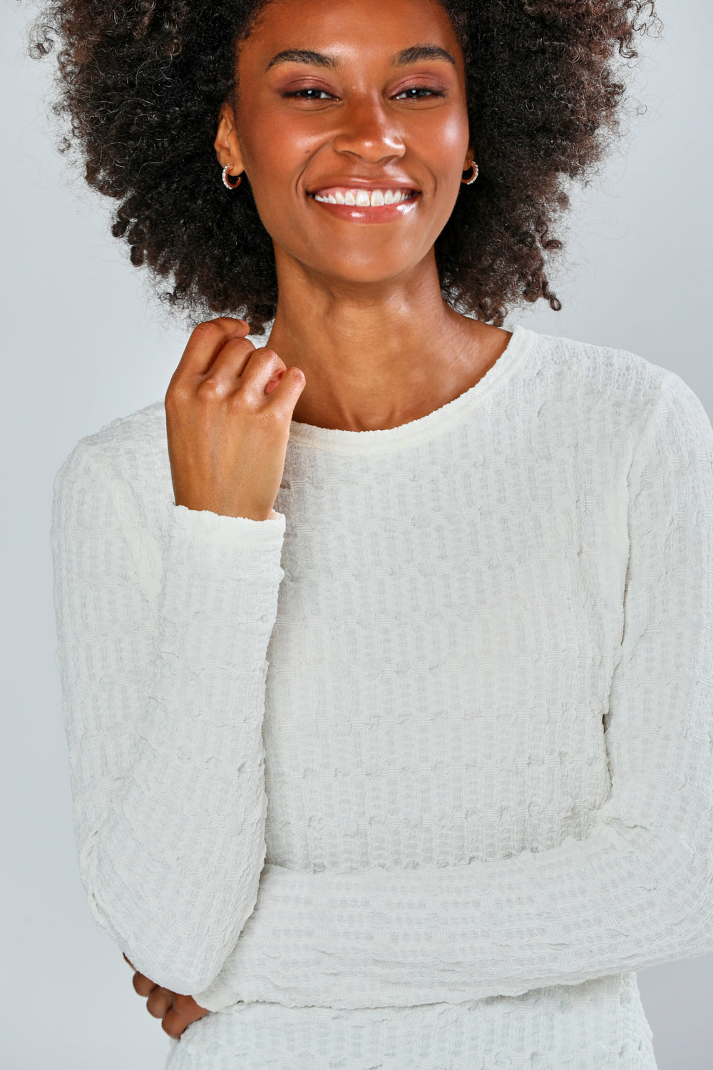 Woman wearing a white top and plaid pants on a plain background