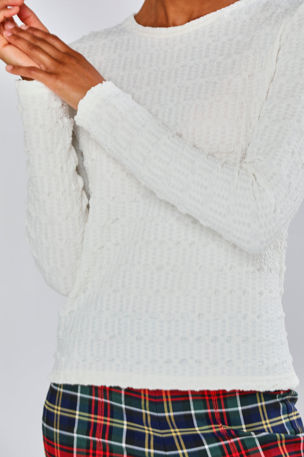 Woman wearing a white top and plaid pants on a plain background