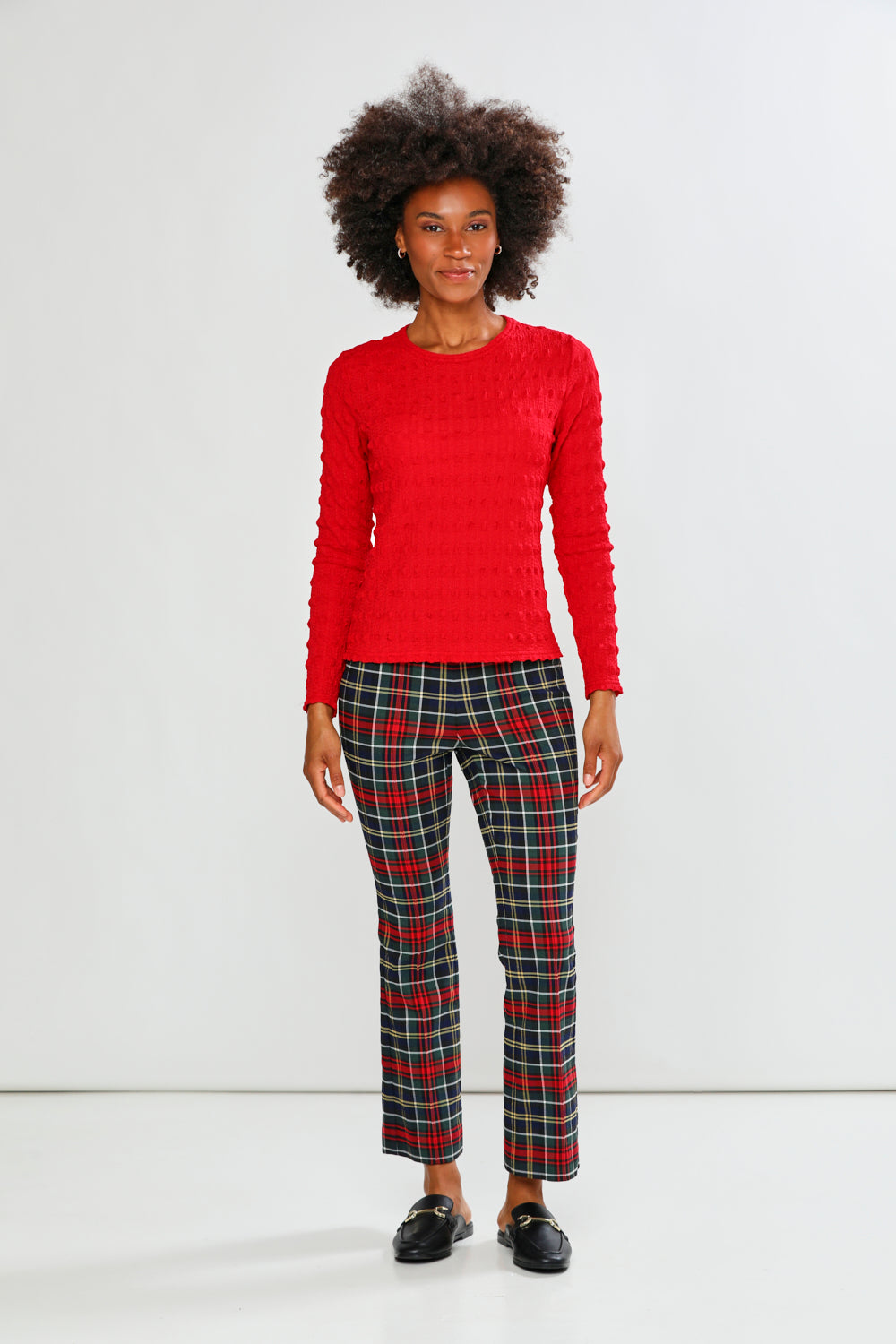 Woman wearing a red top and plaid pants on a white background