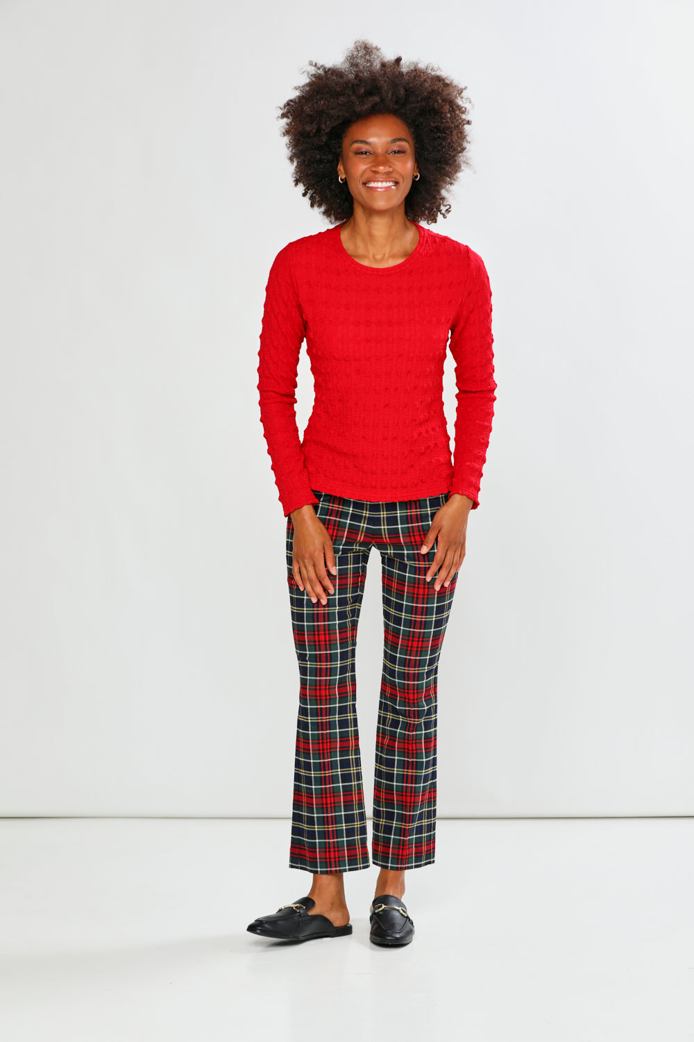 Person wearing a red sweater and plaid pants on a white background