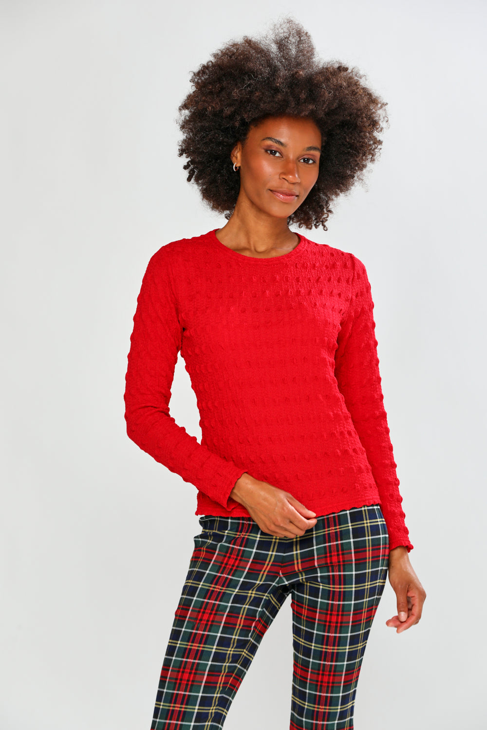 Woman wearing a red top and plaid pants on a white background