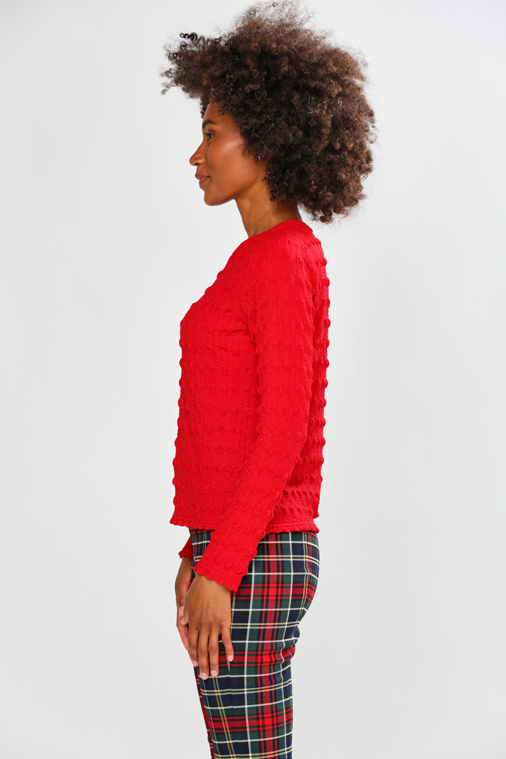 Woman wearing a red top and plaid pants on a white background