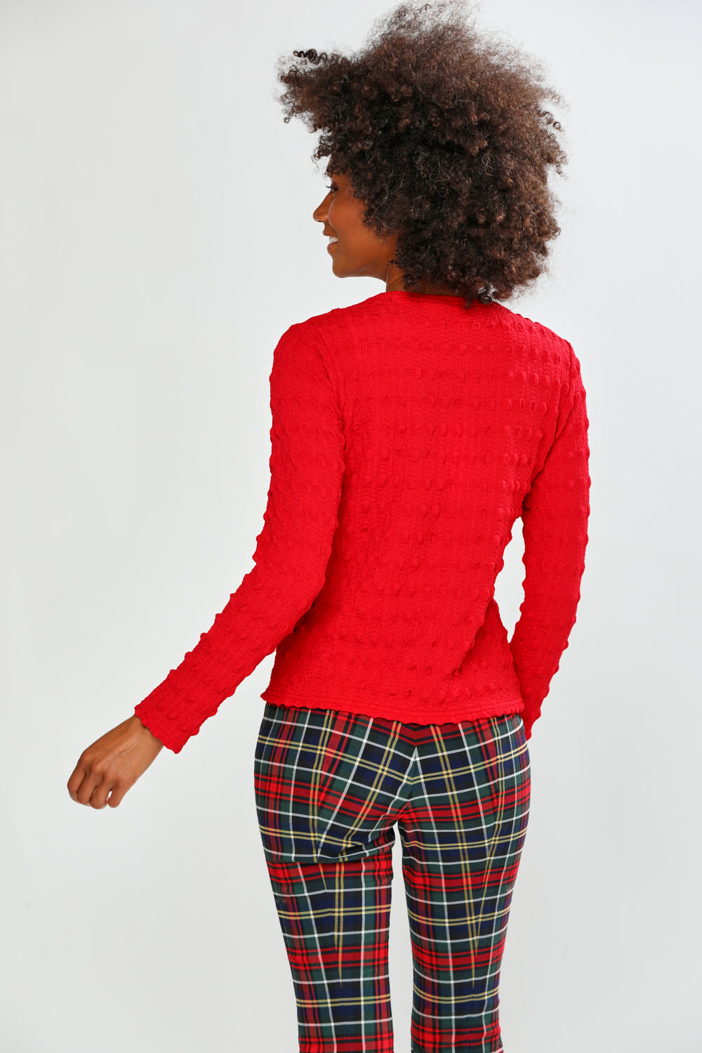Woman wearing a red top and plaid pants on a white background