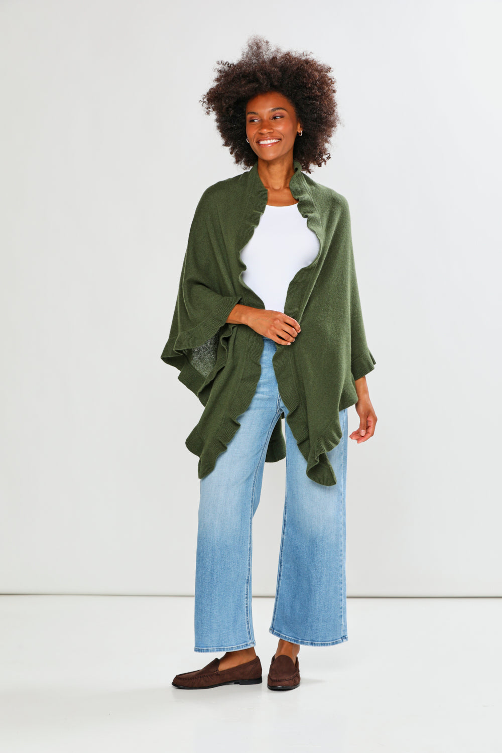 Woman wearing a green jacket, white top, and blue jeans on a white background