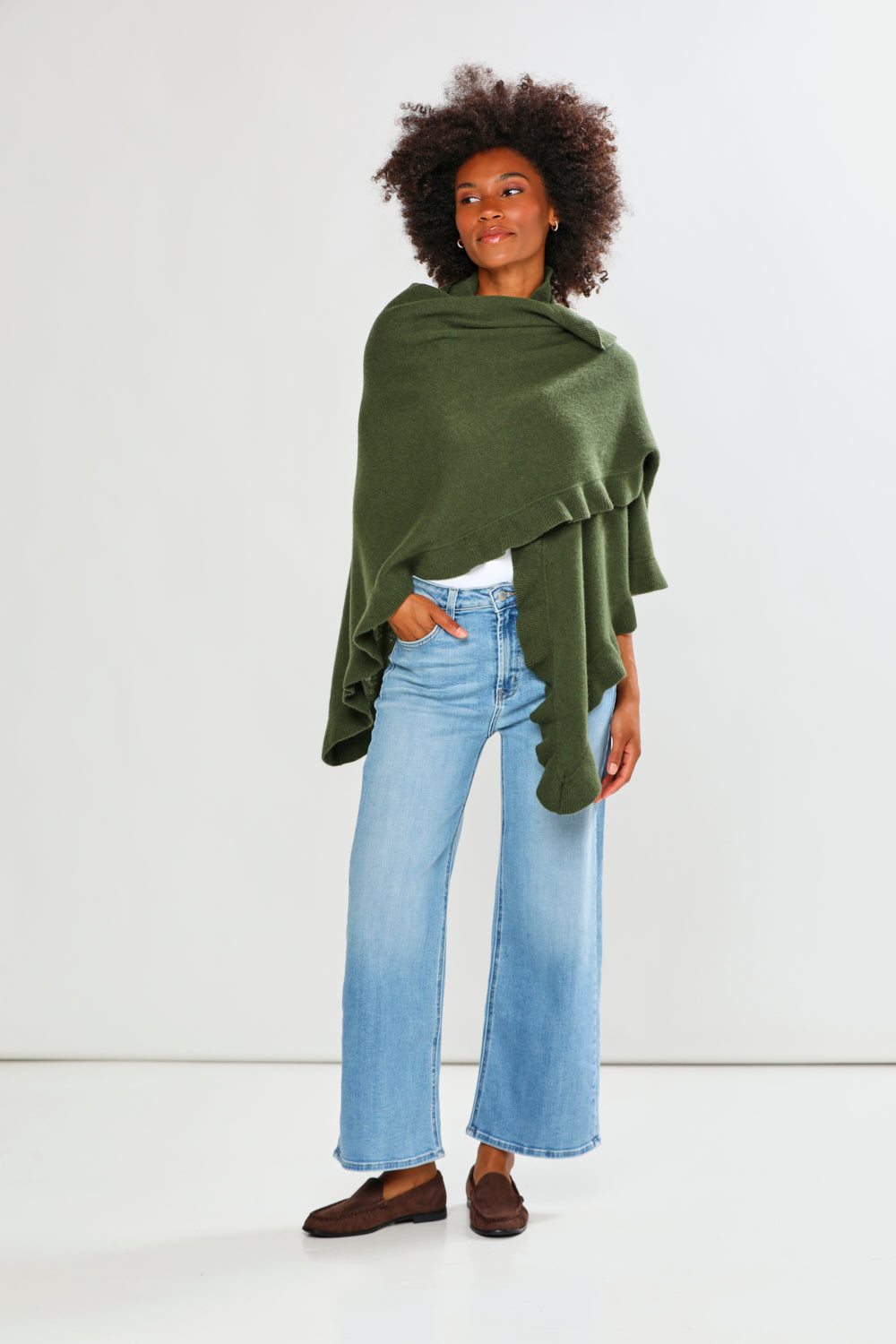 Person wearing a green shawl over a light blue outfit on a white background