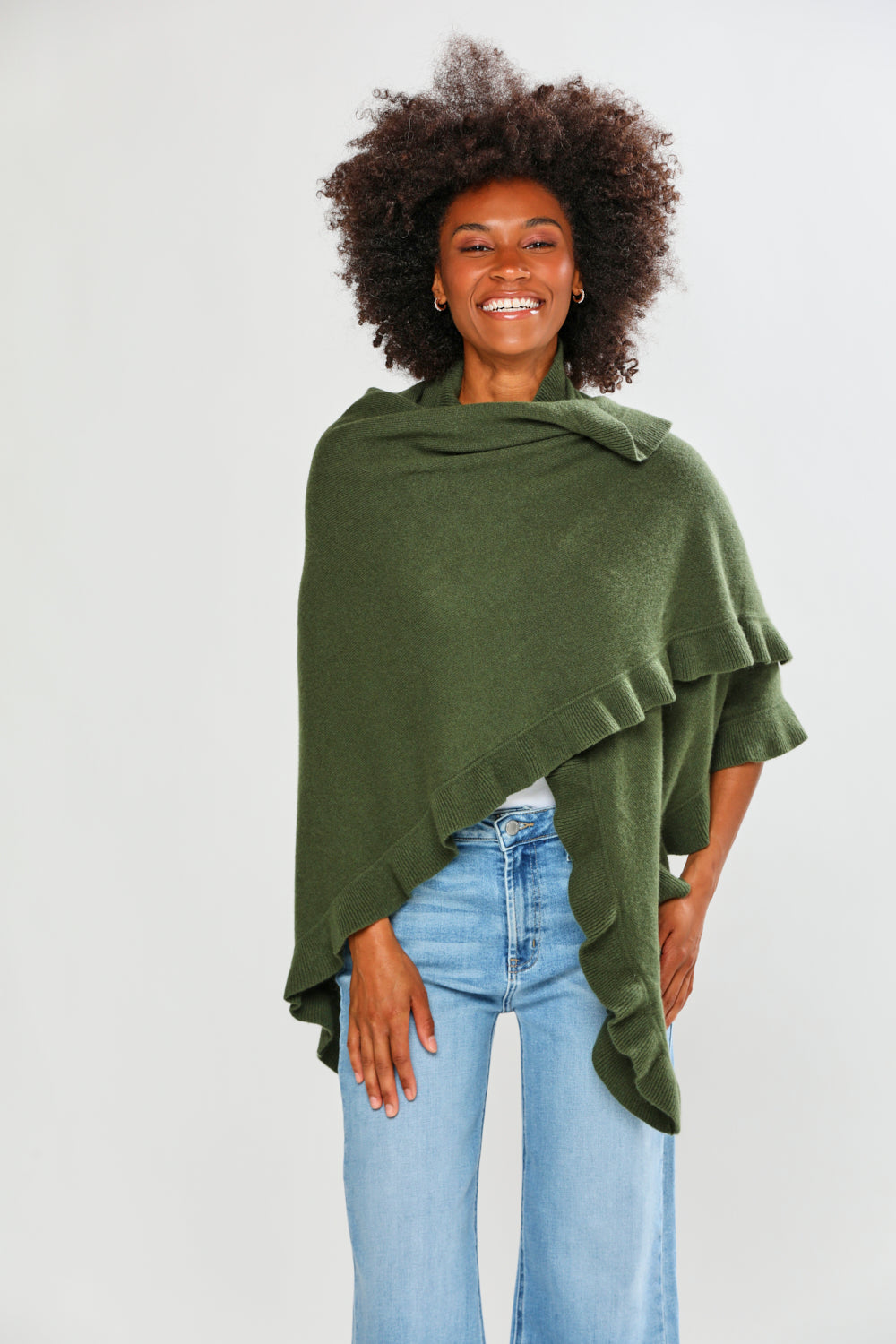Woman wearing a green poncho and blue jeans on a white background