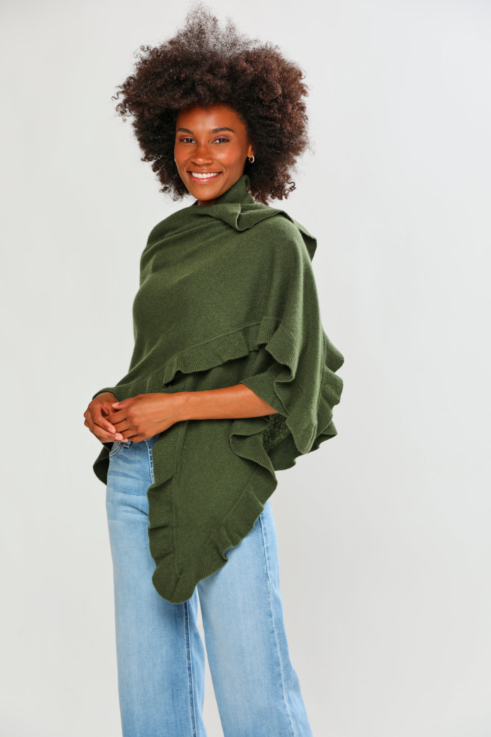 Woman wearing a green poncho over a black top on a white background