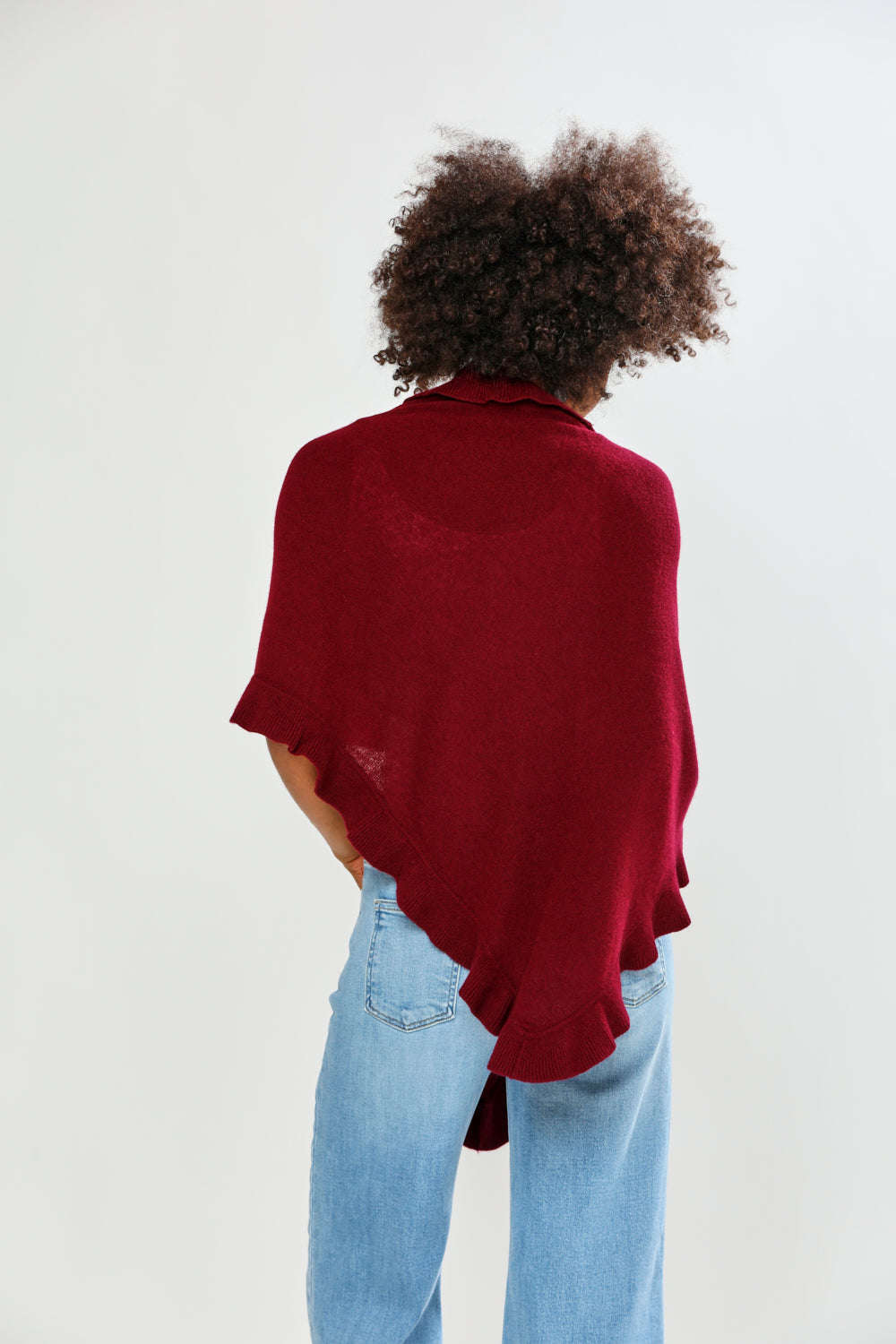 Person wearing a burgundy sweater and light blue jeans on a white background