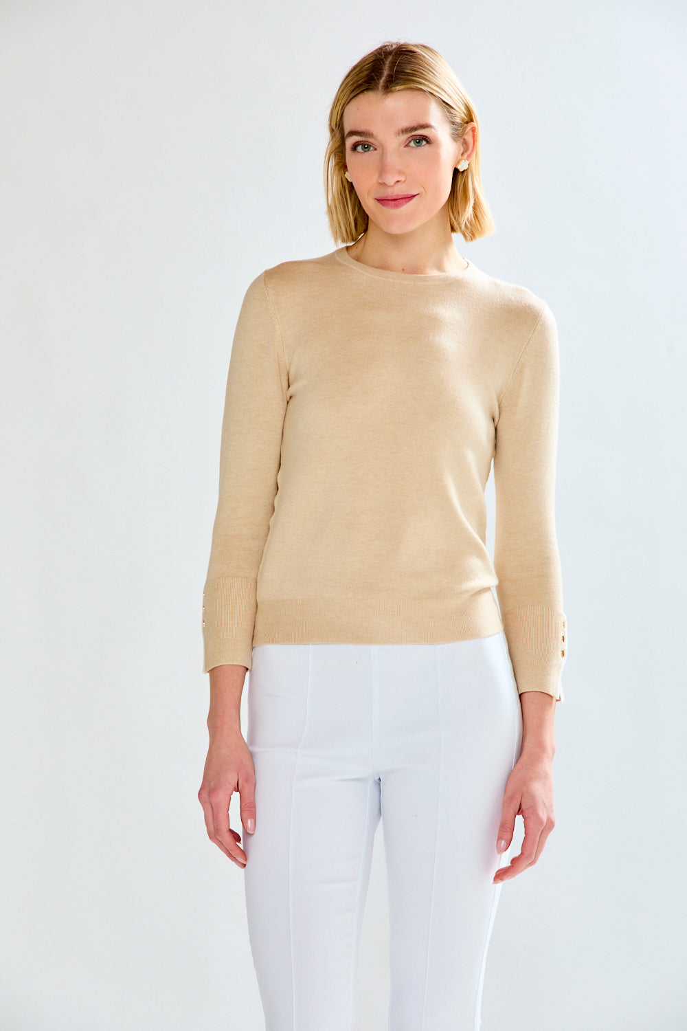 woman in tan sweater and white pants