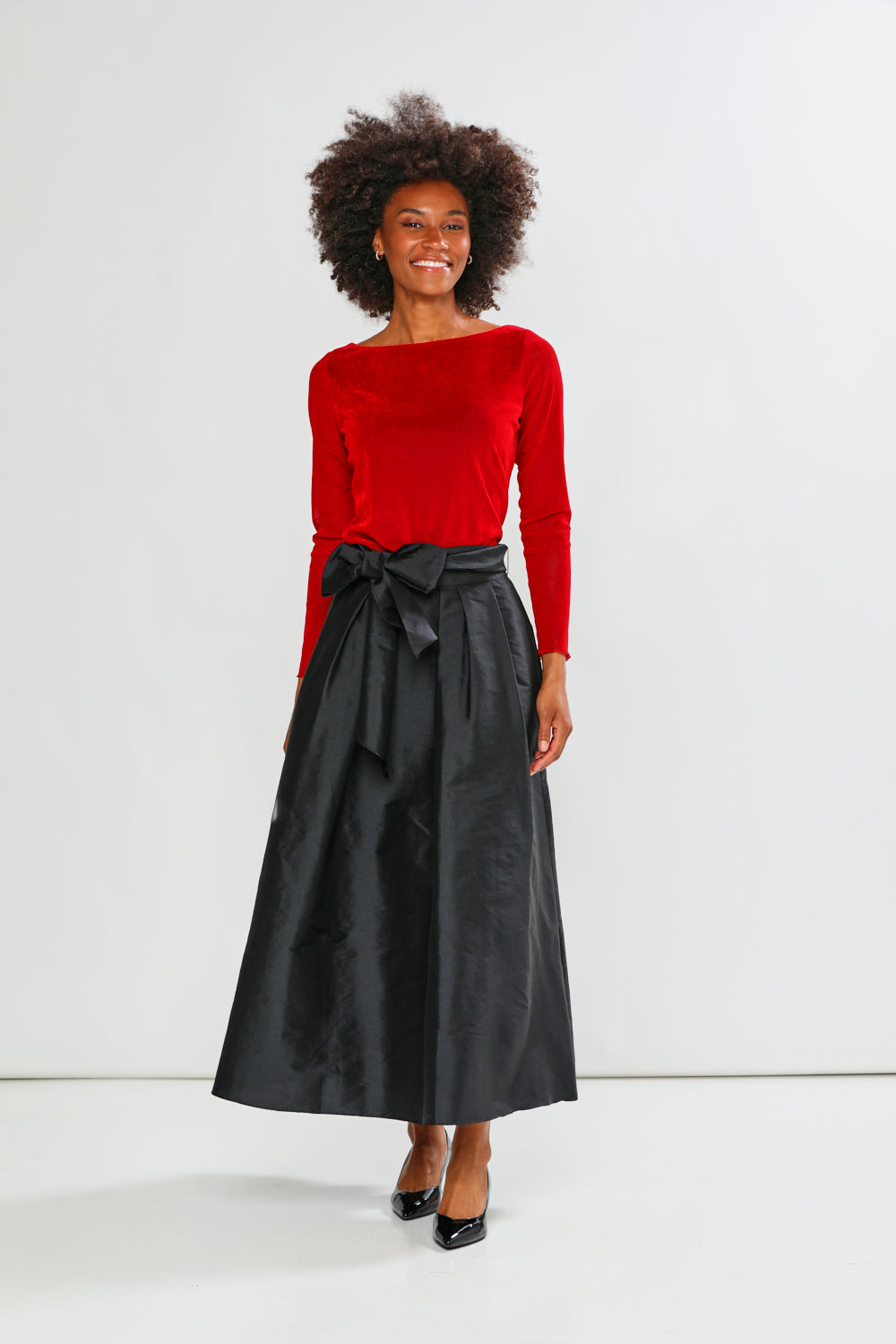 Woman wearing a red sweater and black skirt on a white background