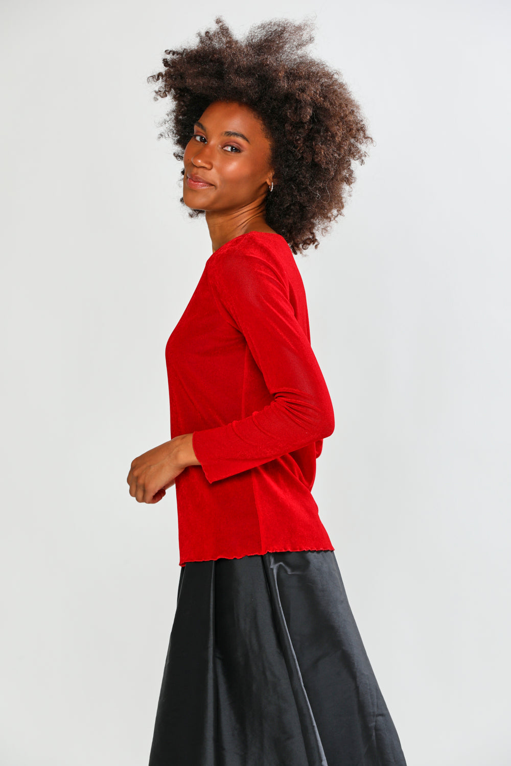 Woman wearing a red long-sleeve top and black pants on a white background