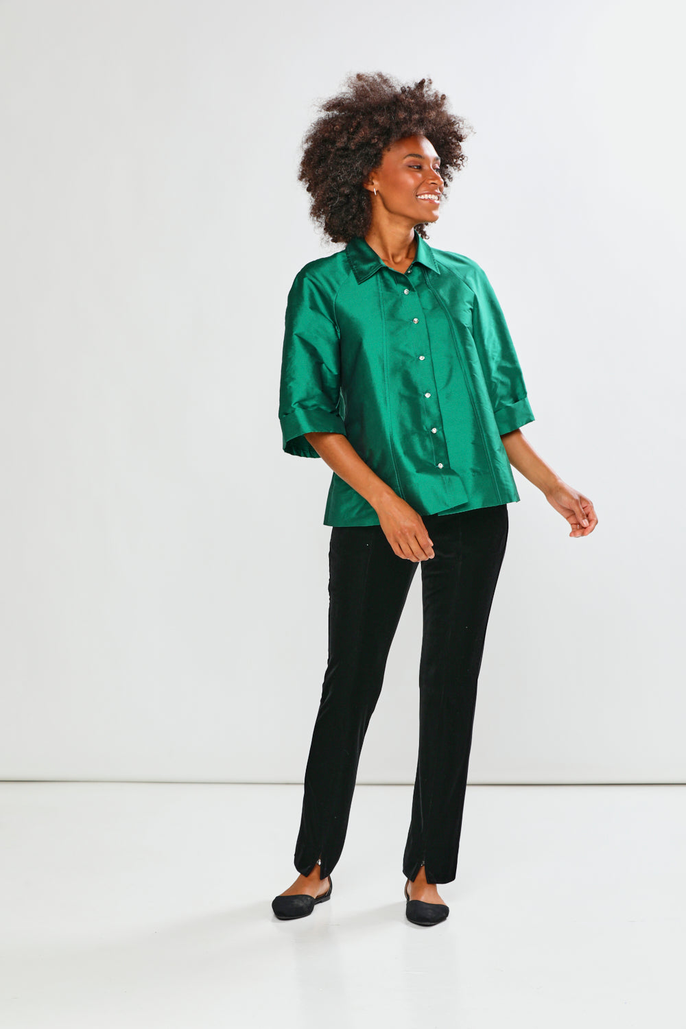 Person wearing a green shirt and black pants on a white background