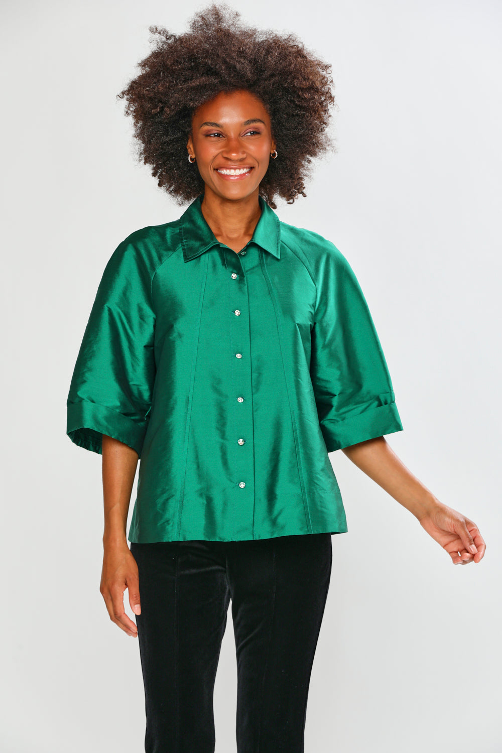 Woman wearing a green blouse with black pants on a white background