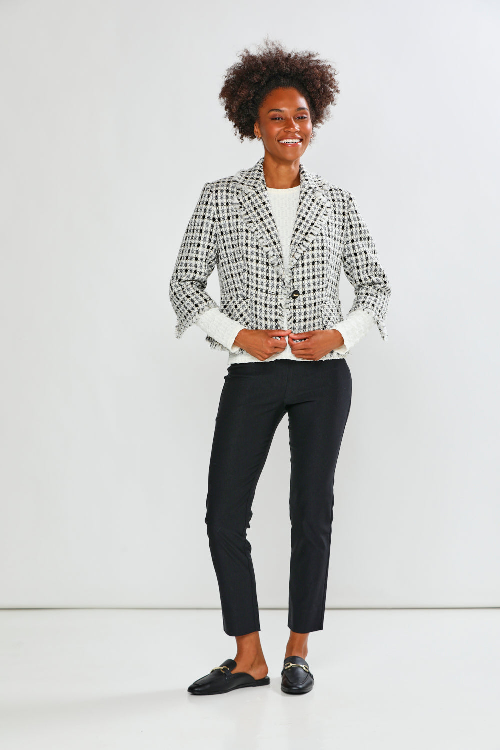 Person wearing a black and white checkered blazer with black pants on a white background