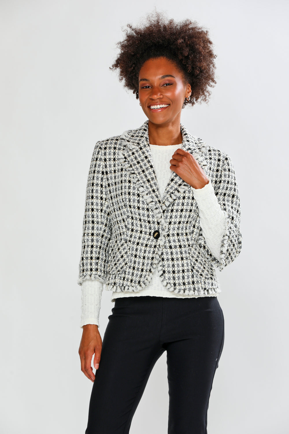Woman wearing a patterned blazer over a white shirt with black pants on a light gray background