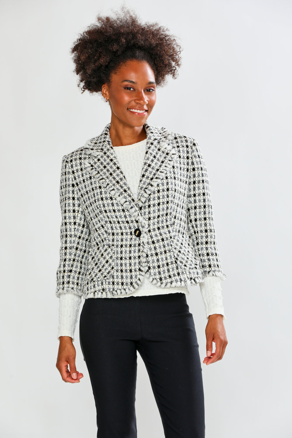 Woman wearing a patterned blazer over a white shirt with black pants on a white background