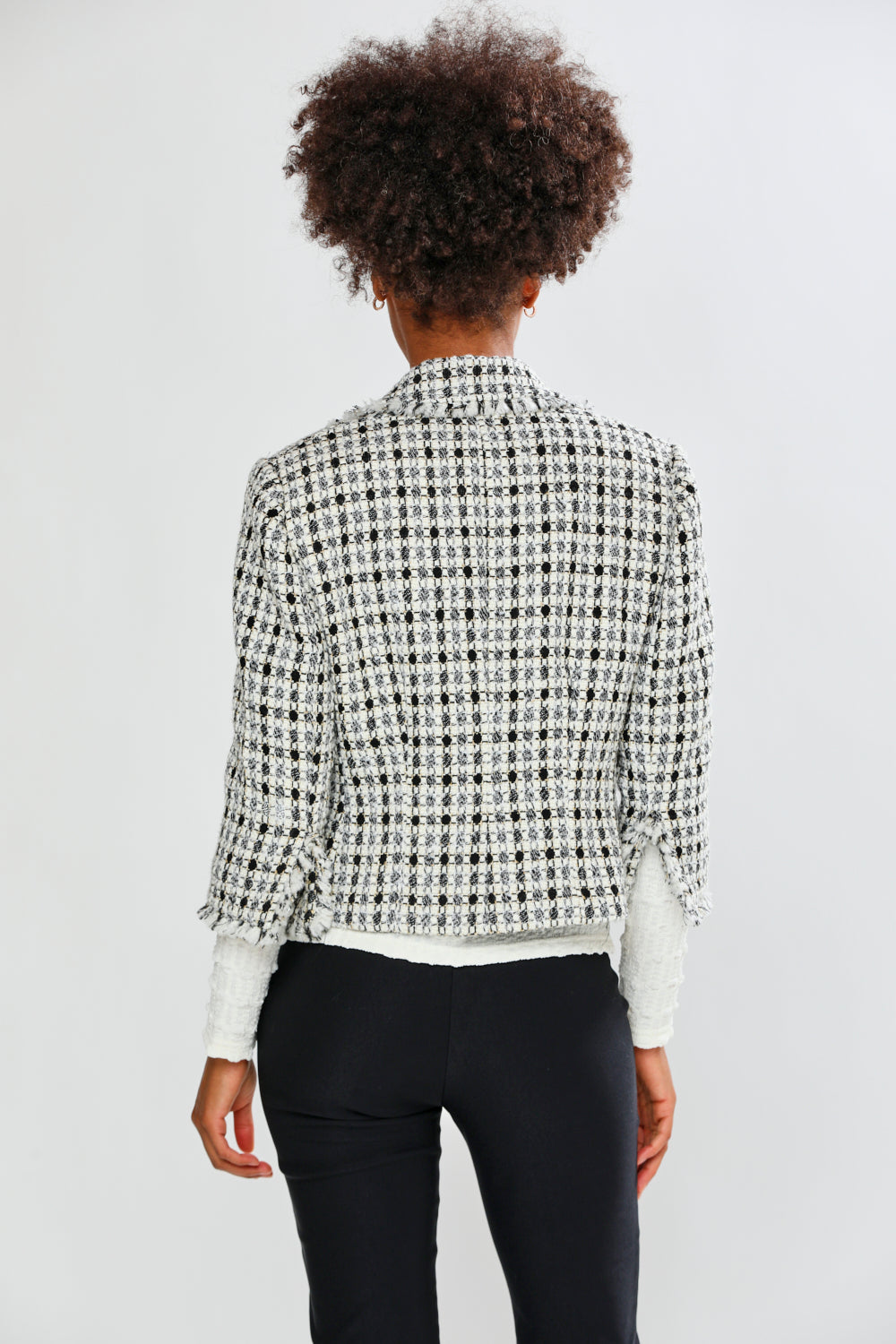 Person wearing a patterned jacket and black pants on a white background