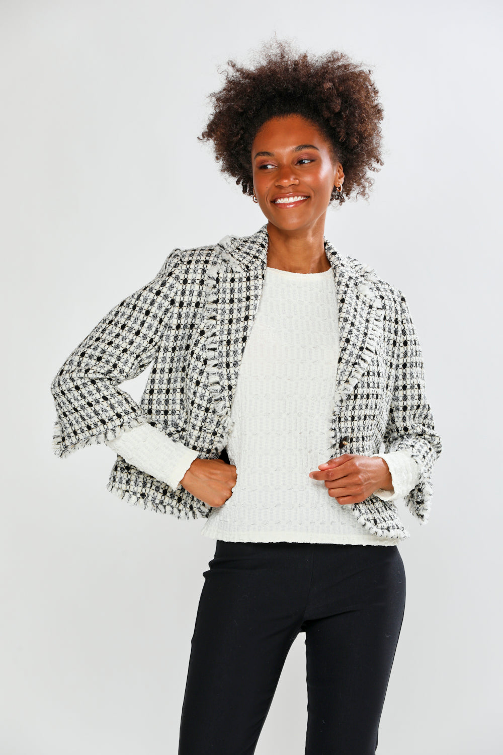 Woman wearing a patterned jacket over a white shirt with black pants on a light gray background