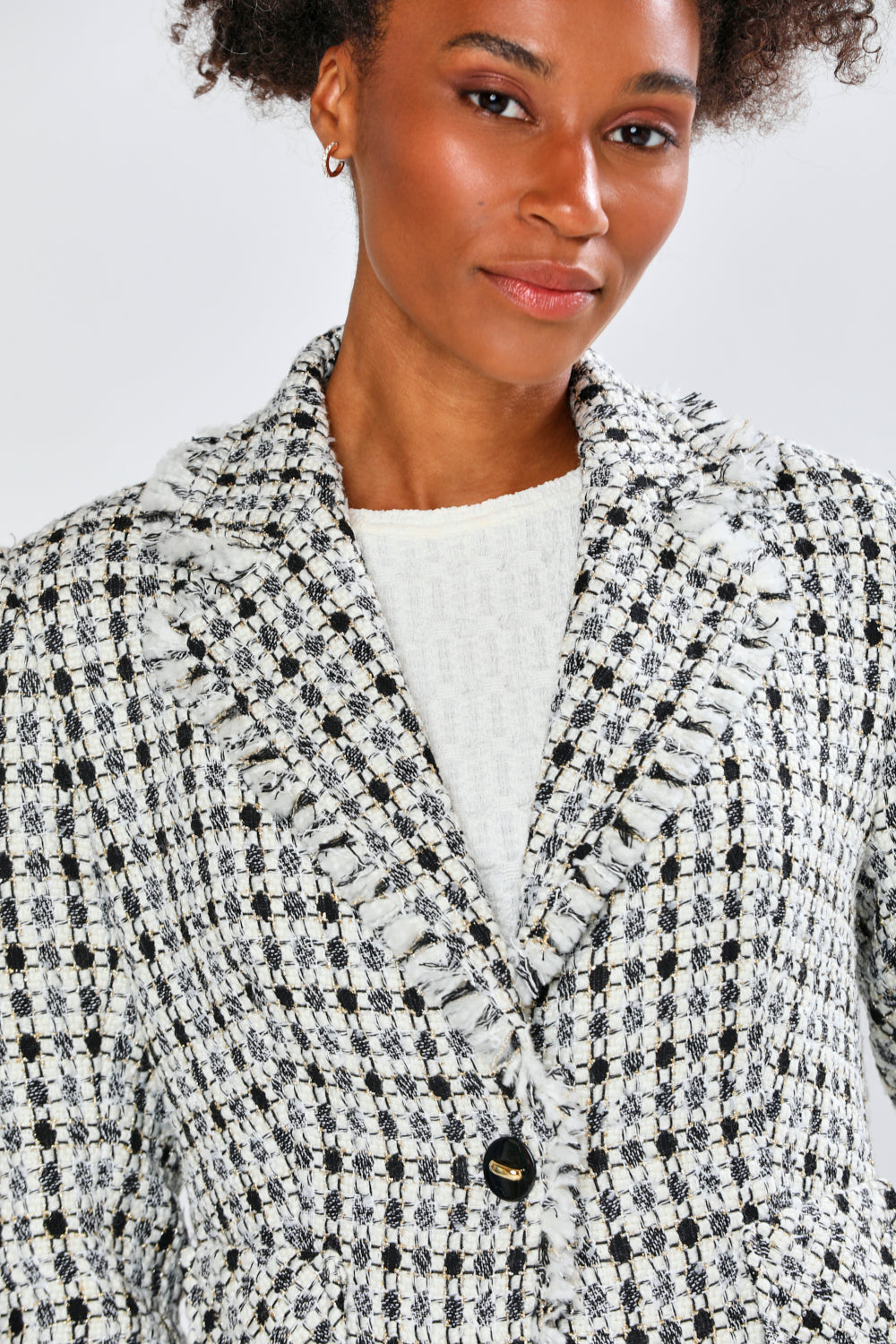 Woman wearing a black and white patterned blazer against a light background