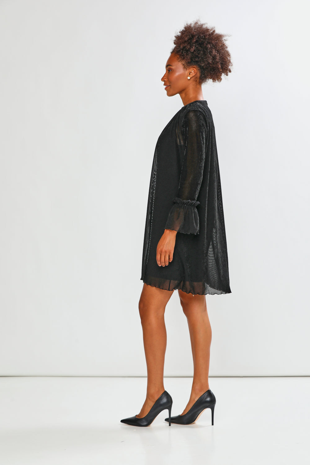 Woman wearing a black dress standing against a white background
