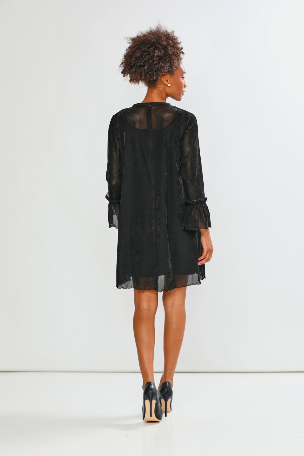 Woman wearing a black dress with sheer sleeves on a white background