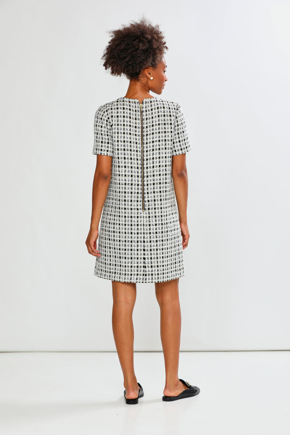 Woman wearing a black and white checkered dress against a white background