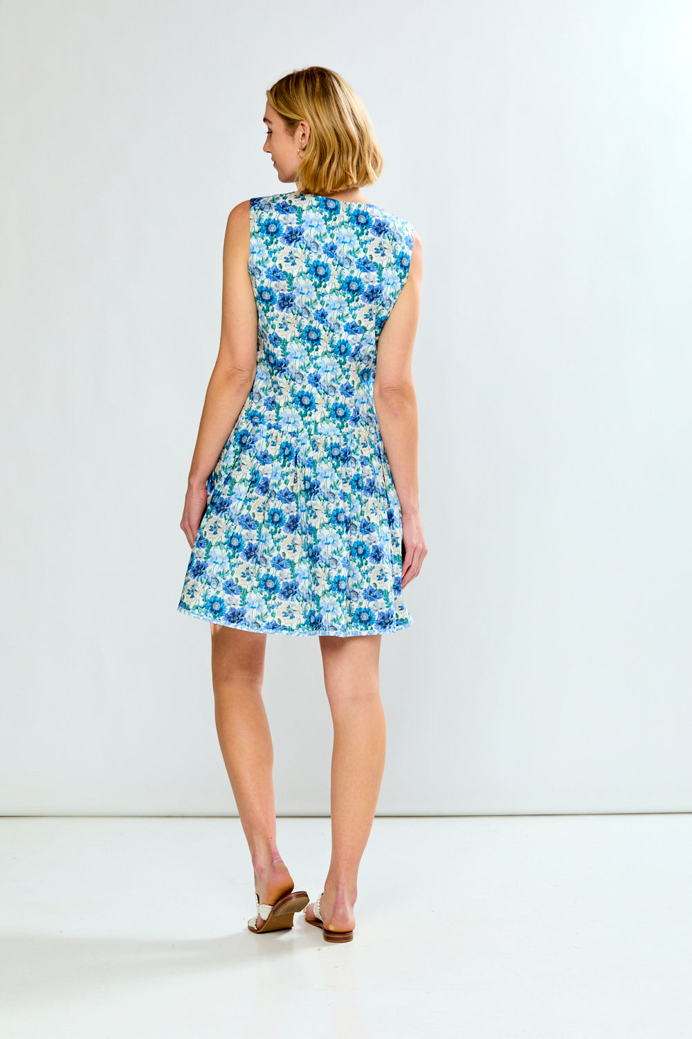 Woman wearing a blue floral dress against a white background
