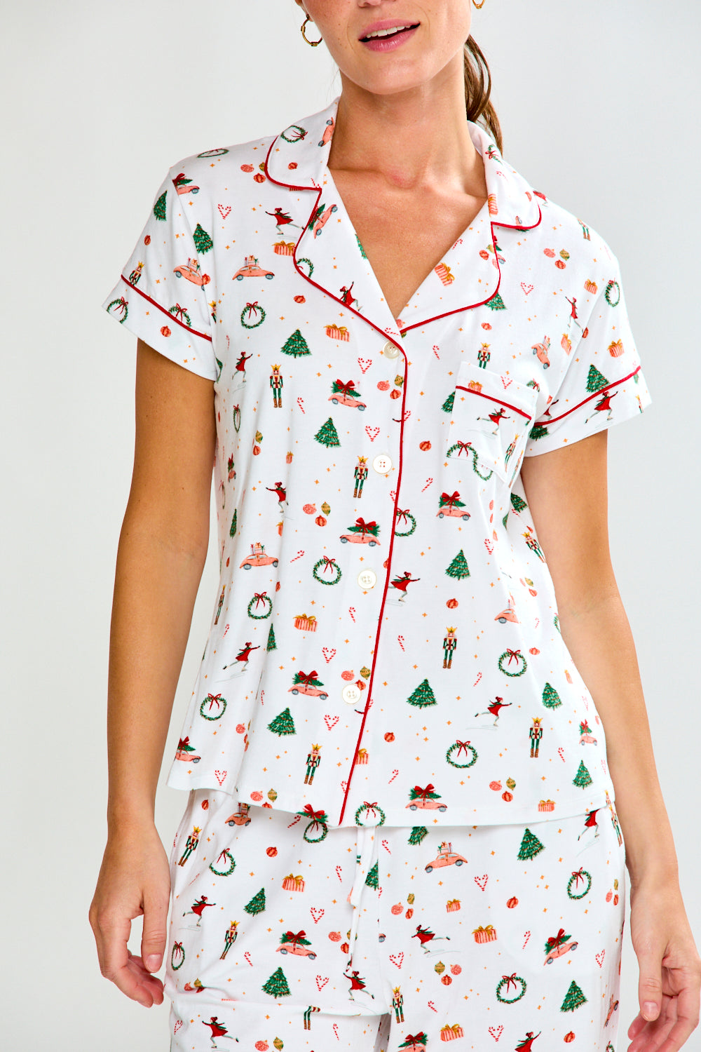 Woman wearing a white pajama set with colorful patterns on a white background