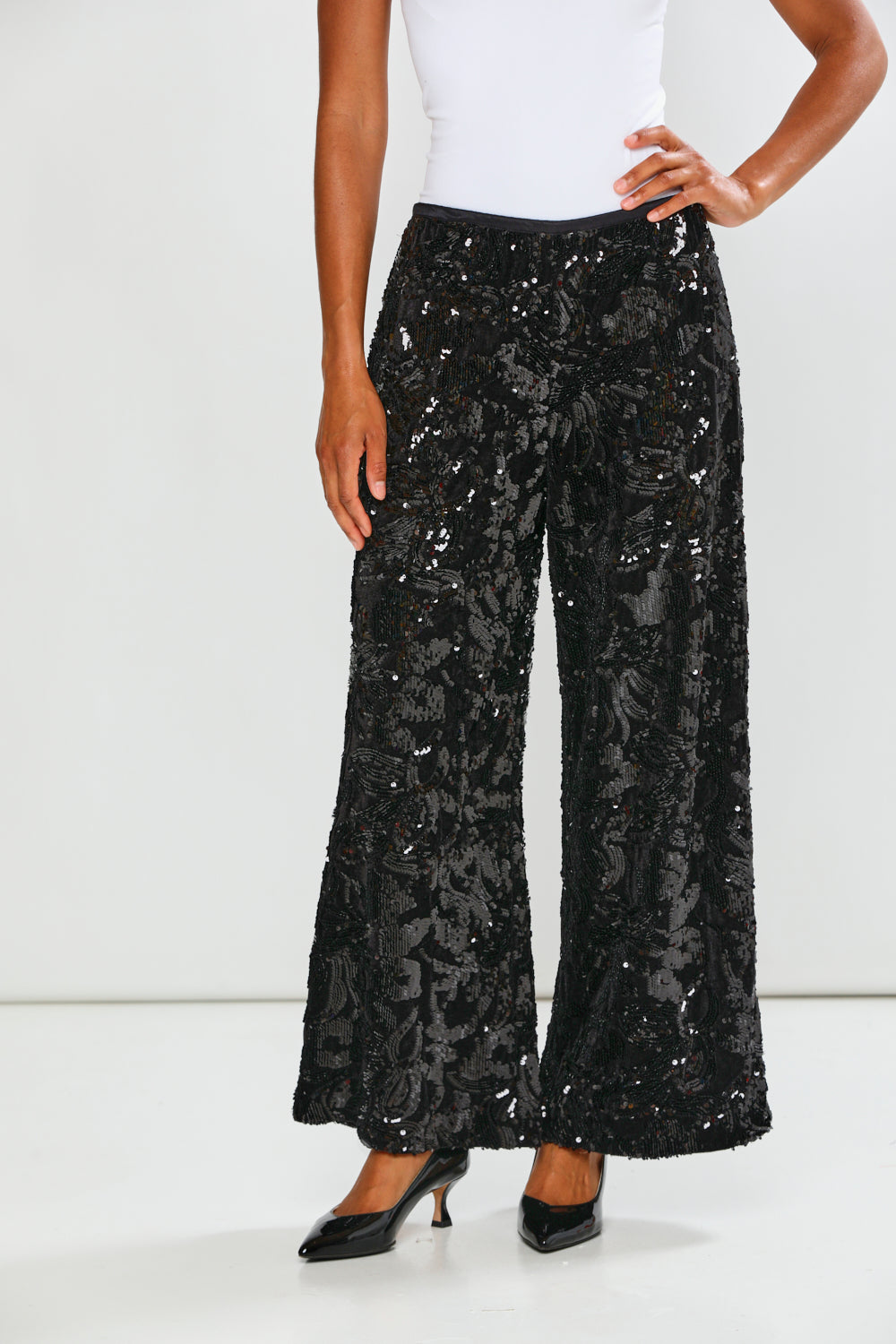 Black sequin pants worn by a person on a white background