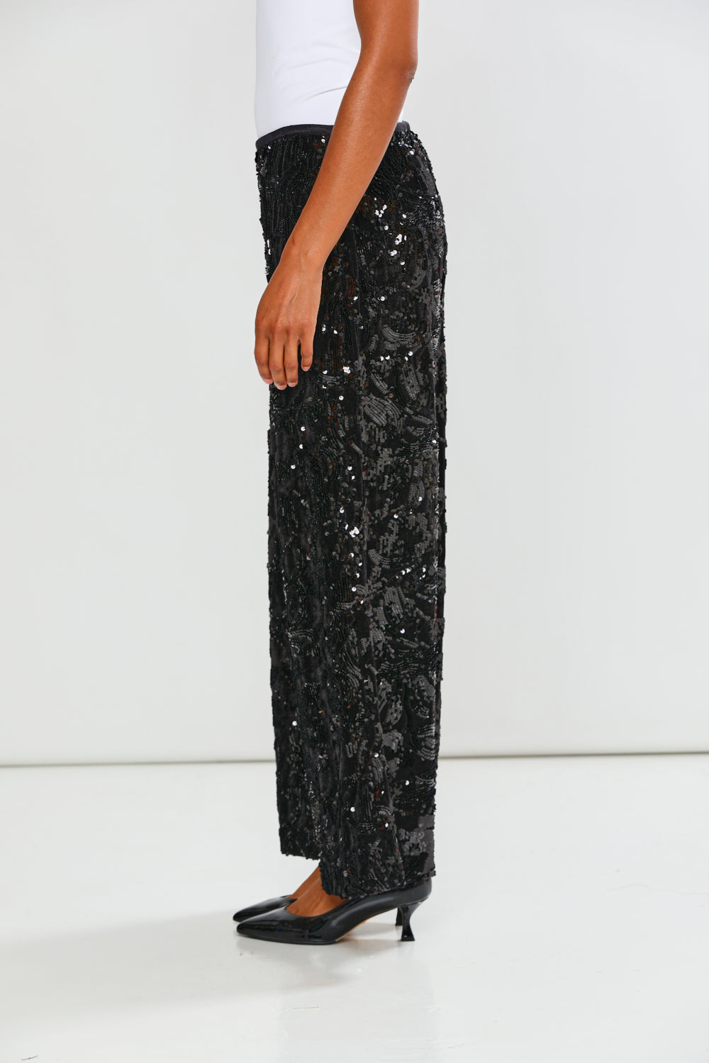 Black sequin pants worn by a person on a white background