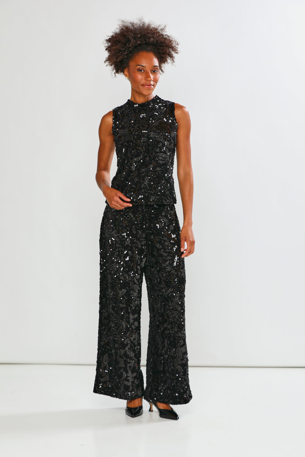 Black sequin pants worn by a person on a white background