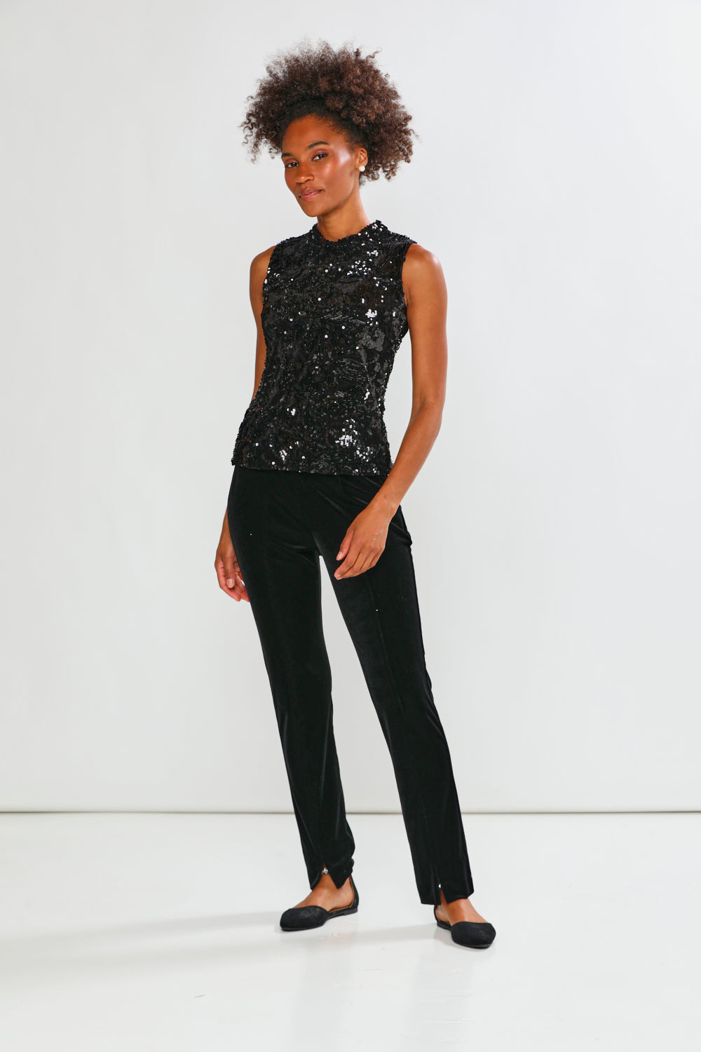 Person wearing a black sequin top and black pants on a white background