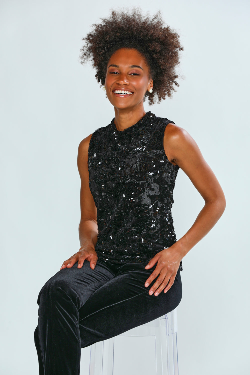 Person wearing a black sequin top and black pants on a white background