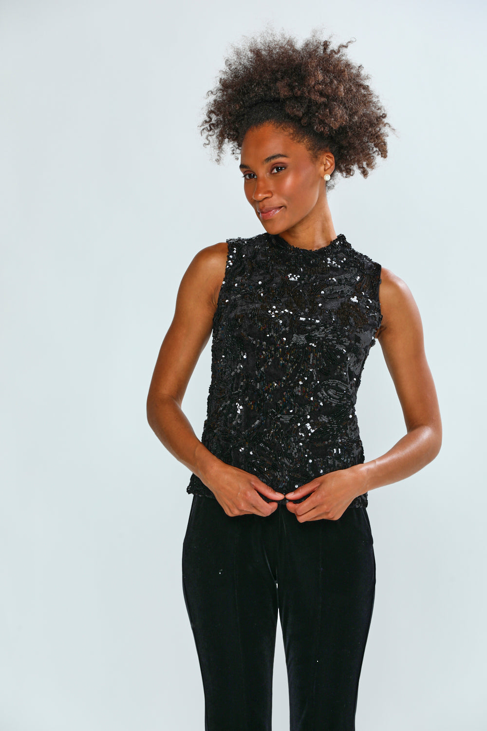 Person wearing a black sequin top and black pants on a white background