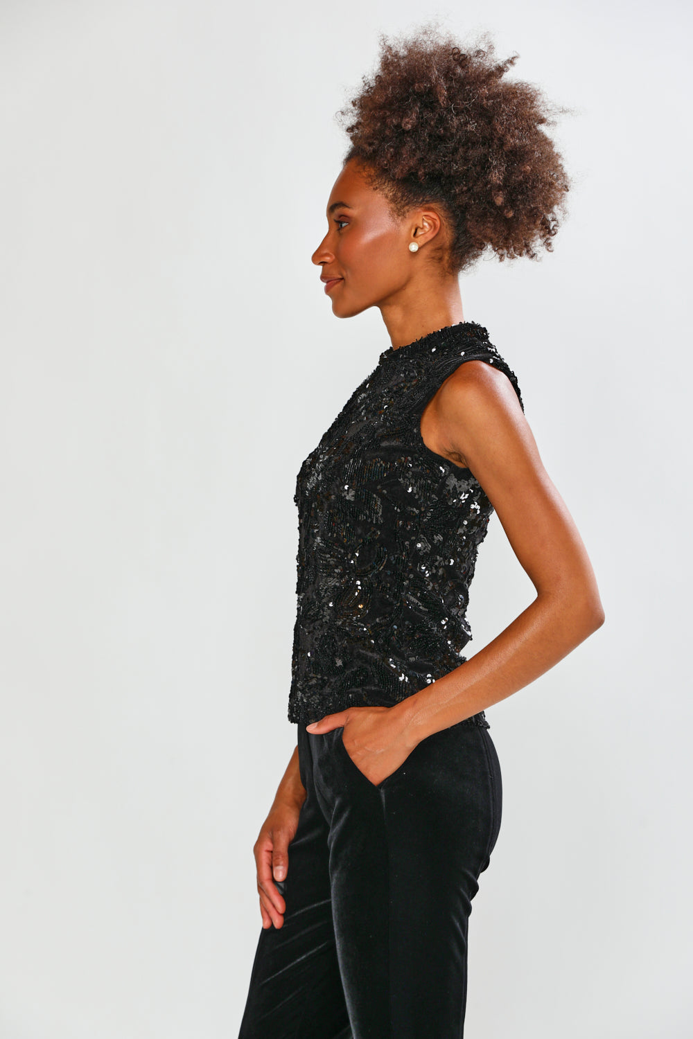 Person wearing a black sequin top and black pants on a white background