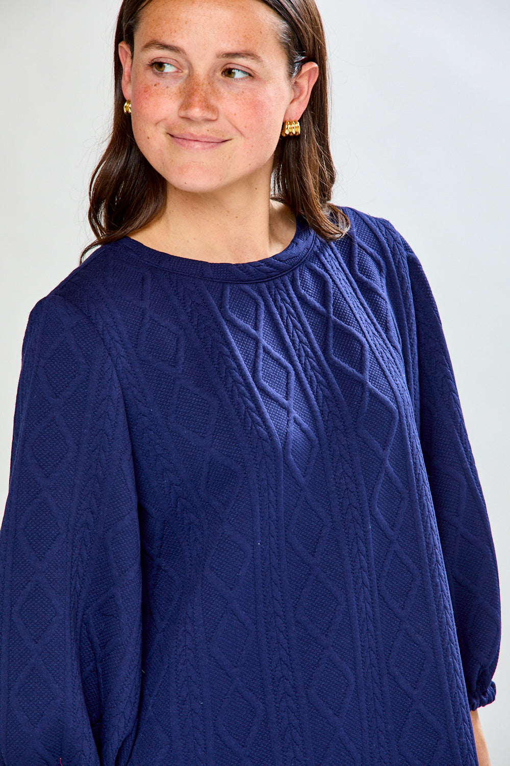 Woman wearing a blue dress with puffed sleeves on a white background