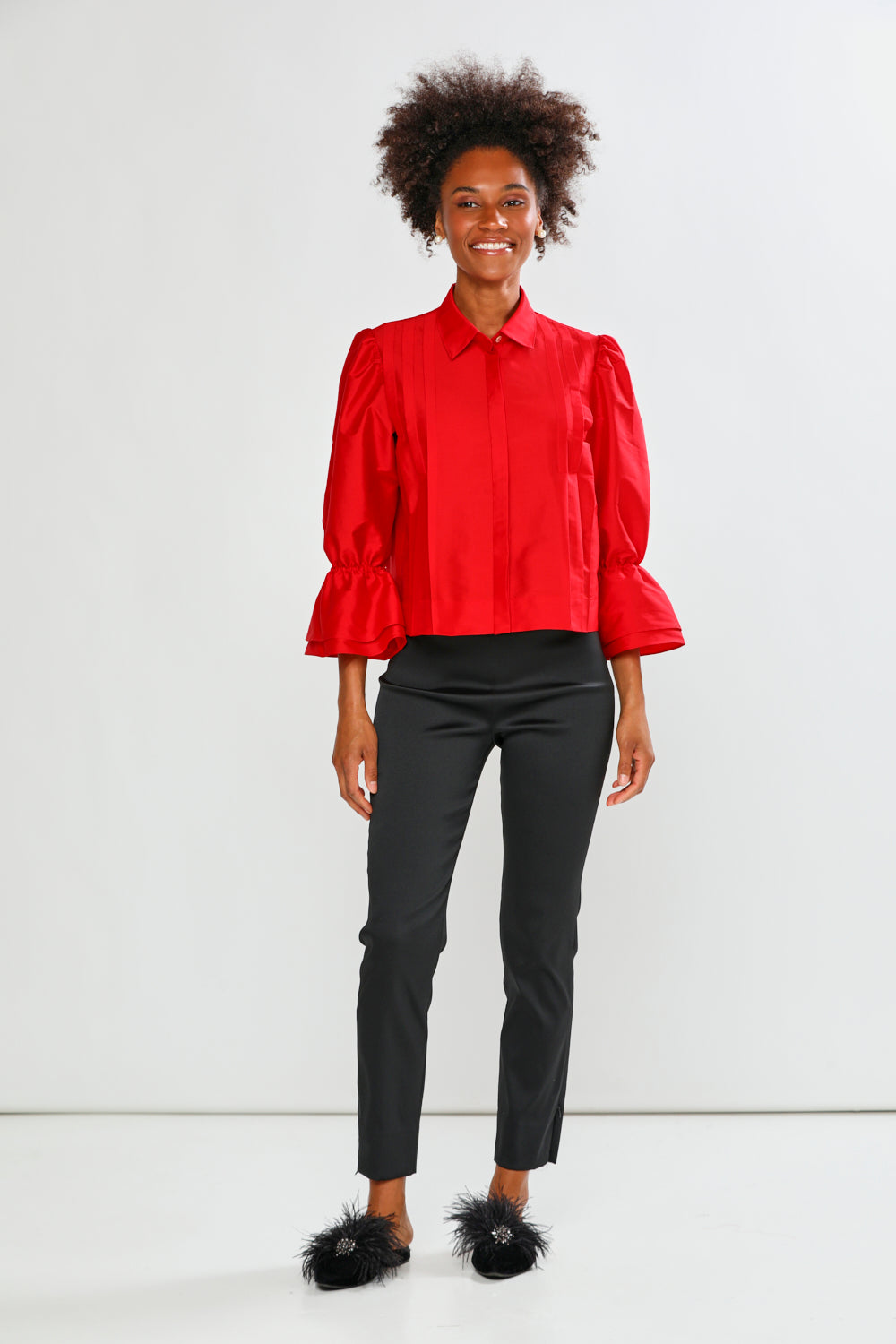 Person wearing a red blouse and black pants on a white background