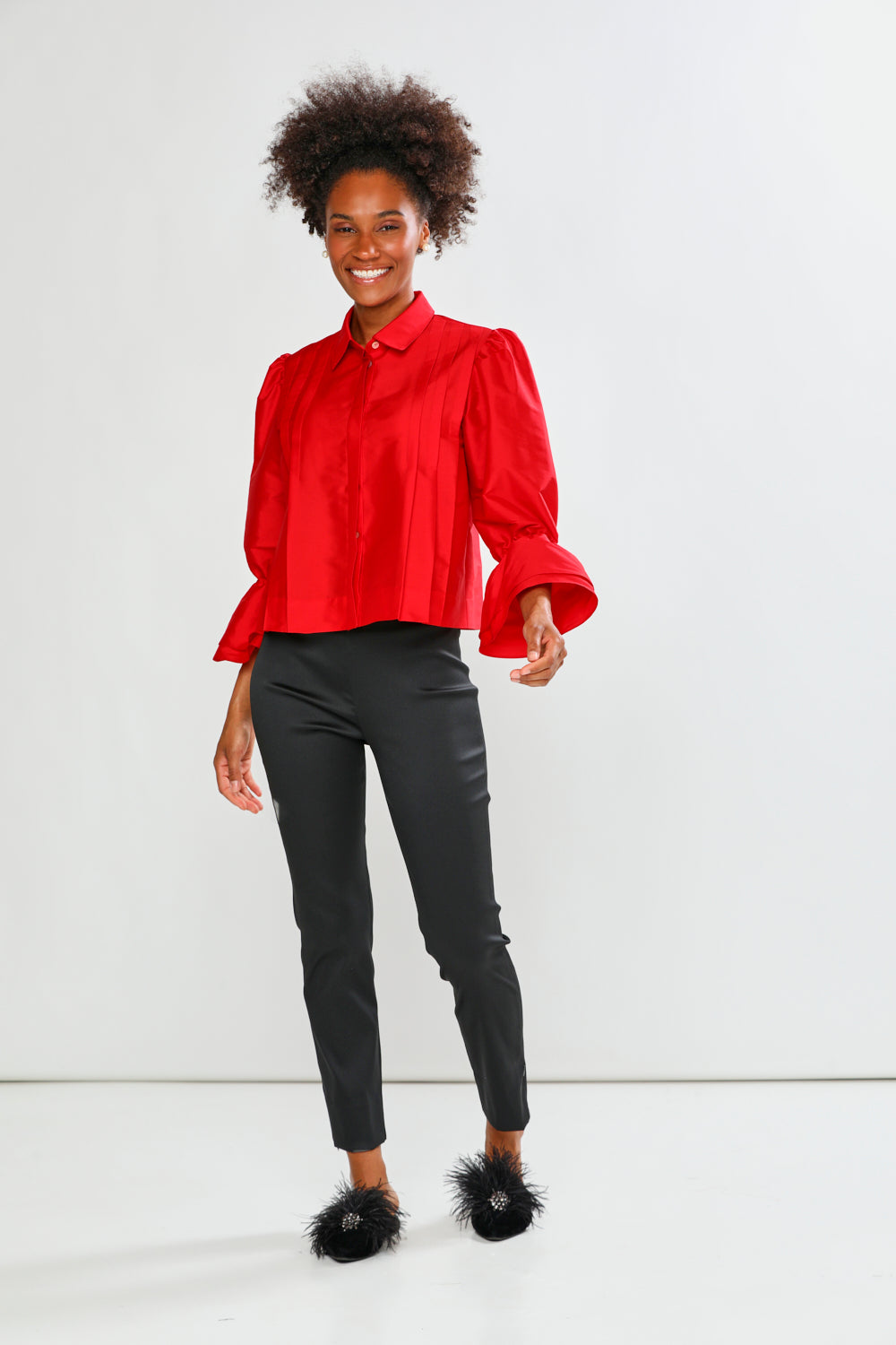 Woman wearing a red blouse and black pants on a white background